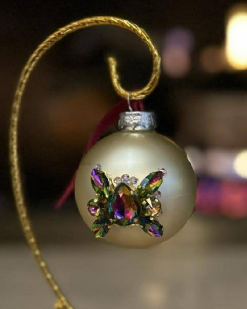 Satin champagne glass Christmas ornament with an iridescent crystal butterfly on a gold stand, Pluma Fine Art